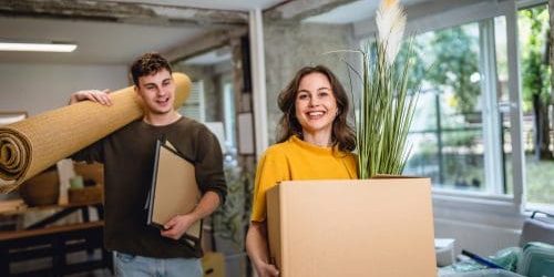 laughing proud couple in love hold box and carpet on relocation day